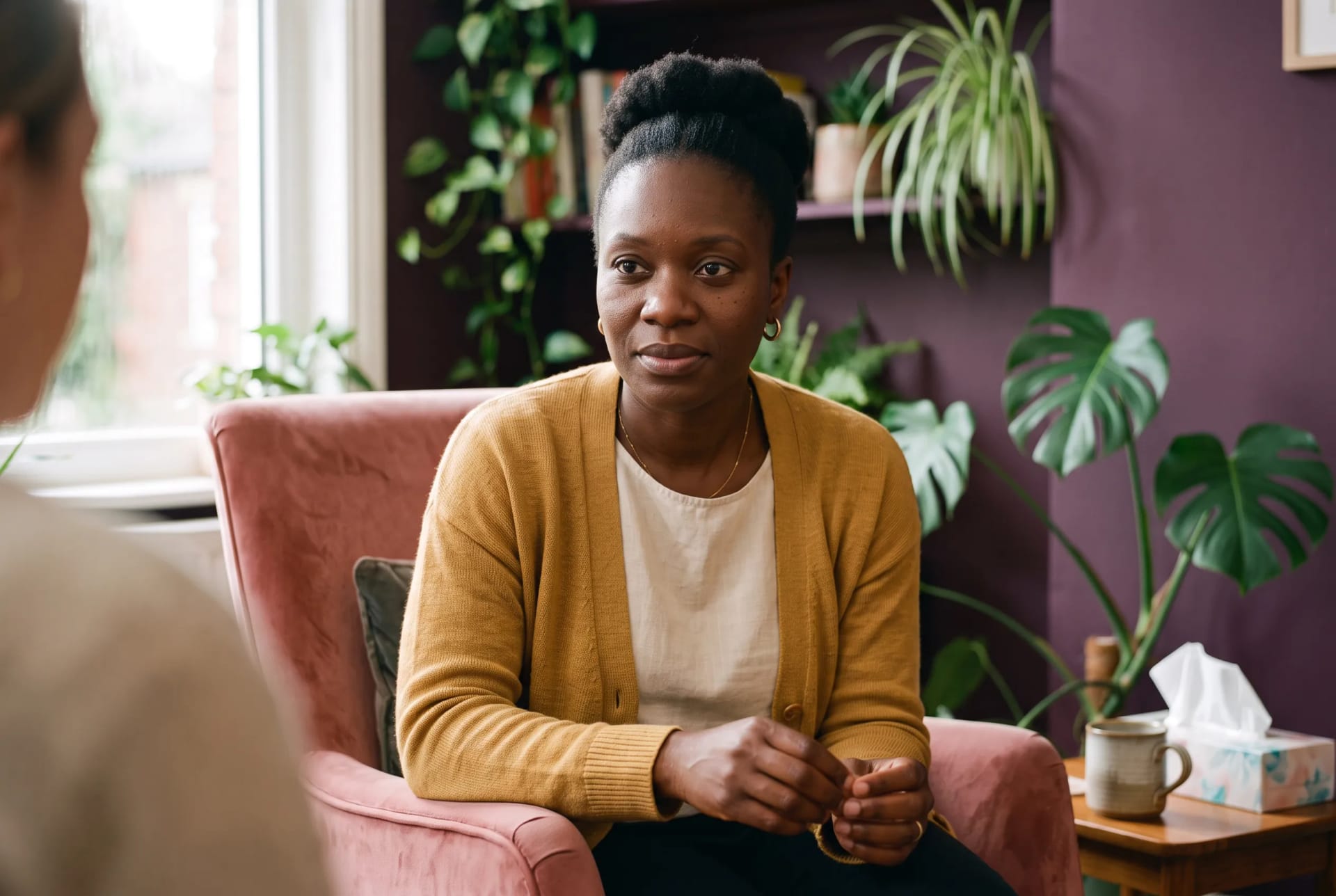 Afia Mensah in listening posture during a session in her Birmingham therapy room, client out of frame